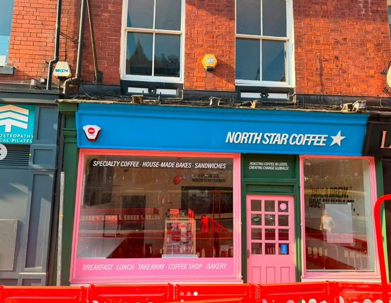 An image of the pink, green, and blue North Star Coffee storefront signage.